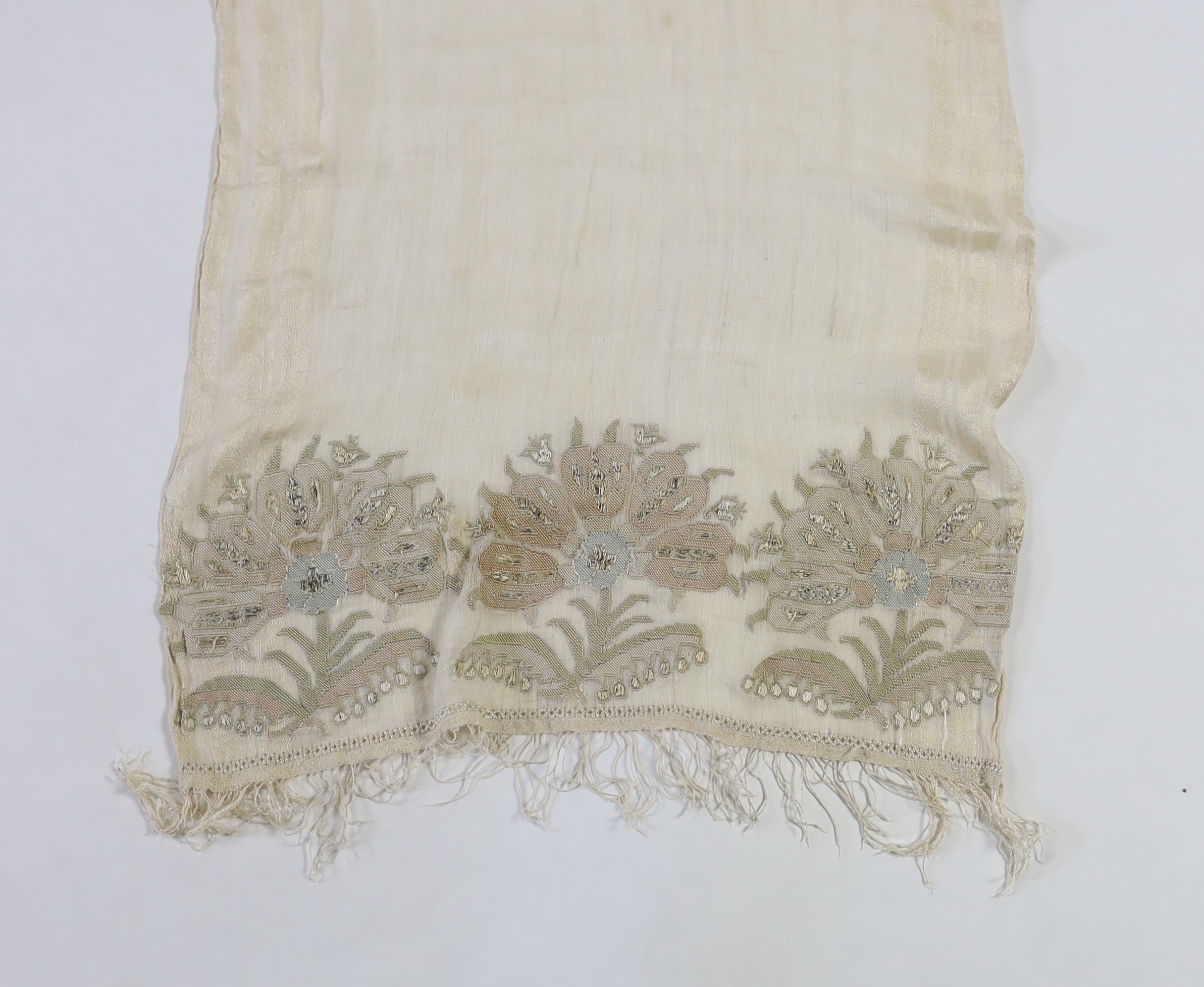 A 19th century Turkish towel, embroidered with flower motifs, in pastel shades, with fine silk fringing embroidered onto a fine hand spun linen, woven with stripes to each side, 48cm wide, 120cm long